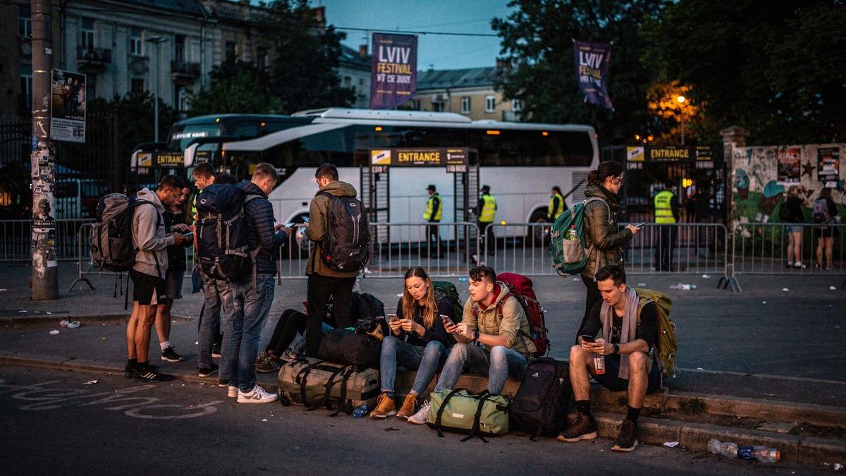 Young travelers with backpacks boarding a coach outside a festival gate in Lviv